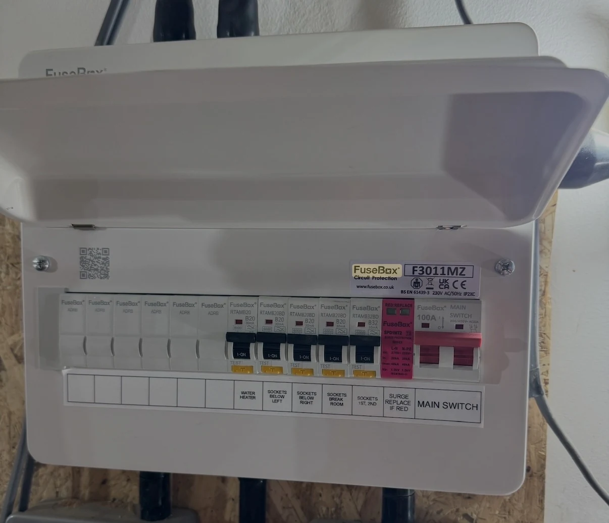 A consumer unit photographed on site: five labelled circuits, a surge protection device and a 100 amp main switch